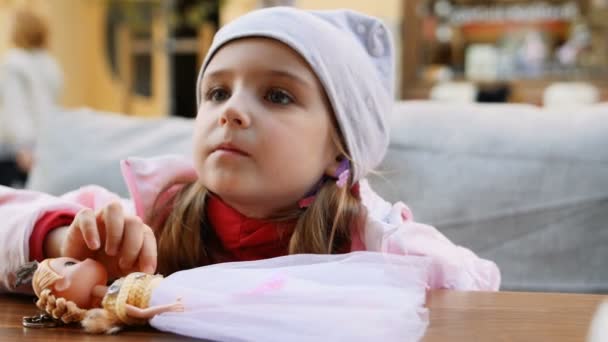 kleines Mädchen spielt Puppe im Café auf der Straße - Filmmaterial, Video