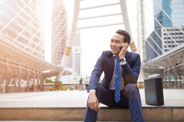 Бизнесмен сидит на лестнице во время звонка по телефону, с выключенным
 - Фото, изображение