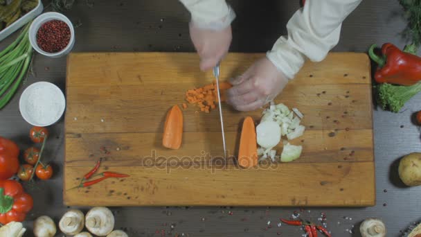 Szef kuchni kawałki cebulę i marchew. Cebulę i marchew jako składnik do produkcji zupy lub innego naczynia. Widok z góry - Materiał filmowy, wideo