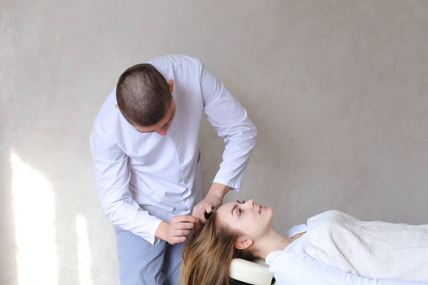 Handsome guy massage therapist doing head massage for girl clien - 写真・画像
