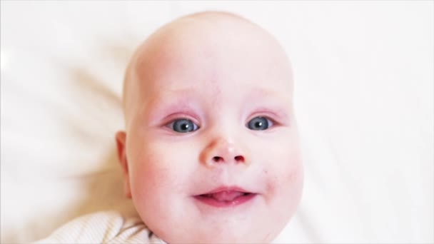 Slow motion portret van blauwogige jongetje glimlachend naar iemand achter de camera - Video