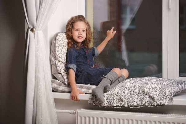 Kleines Mädchen zu Hause auf der Fensterbank - Foto, Bild