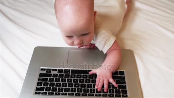 Портрет восхитительного 6-месячного мальчика, лежащего в постели и играющего с ноутбуком
 - Кадры, видео