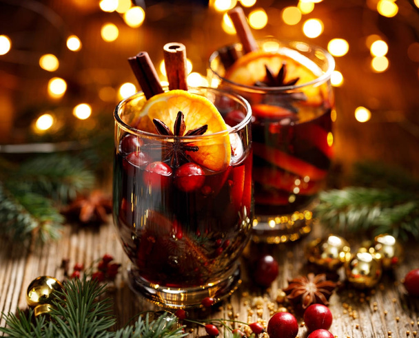 Mulled red wine with addition of citrus fruits, cranberries, cinnamon sticks, cloves and anise stars. Delicious christmas drink - Foto, imagen