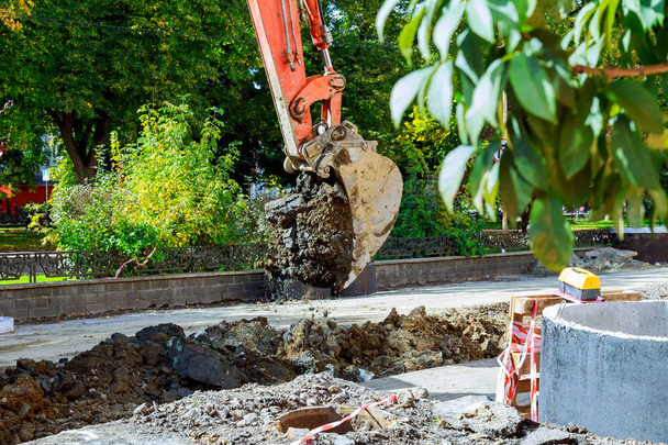 Excavadora con orugas metálicas que descarga suelo en construcción durante trabajos de movimiento de tierras
 - Foto, imagen