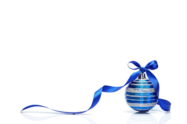 blauwe bal met het Kerstmis met lint buigen geïsoleerd op witte achtergrond - Foto, afbeelding