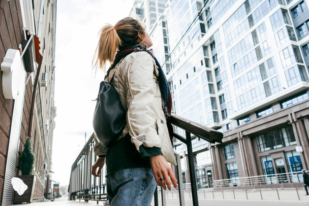 stylish young girl in a white jacket walking around the city, looking up - Valokuva, kuva