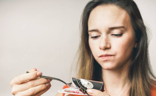 Legrační obličej žena jíst užitečné dietní jogurt, na bílém pozadí - Fotografie, Obrázek
