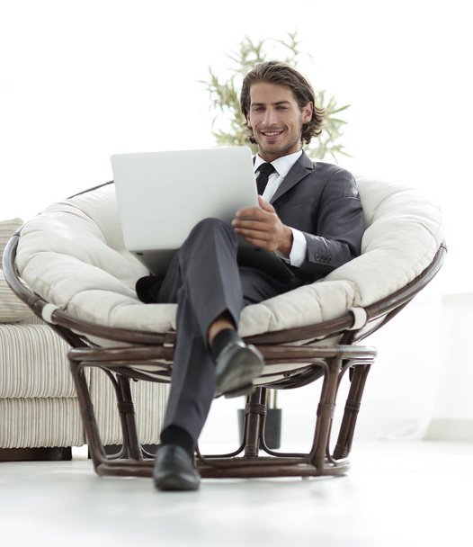 successful businessman with laptop sitting in a large comfortable armchai - Photo, Image