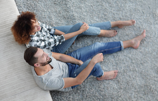 newlywed couple sitting on a carpet in a new living room - Foto, afbeelding