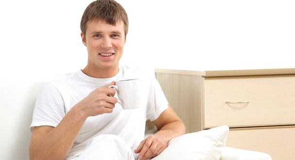 Handsome casual man sitting on couch having coffee at home. - Photo, image