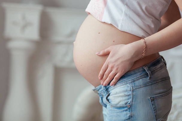 Mujer embarazada de siete meses en jeans. Vista frontal de cerca
 - Foto, Imagen
