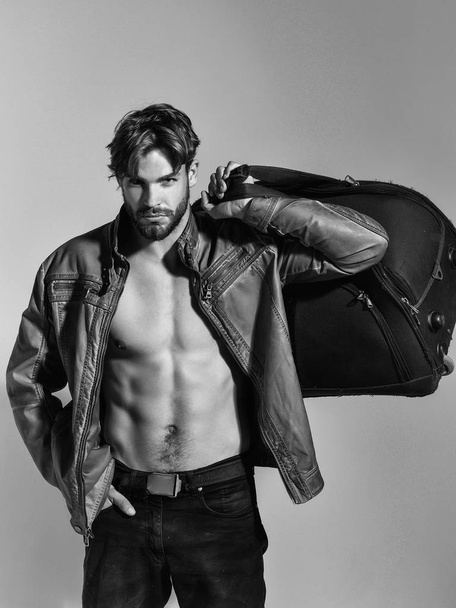 muscular bearded man with sexy body holds big bag, suitcase - 写真・画像