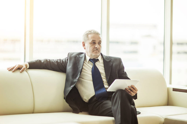 successful businessman with digital tablet sitting on sofa in the office. - Fotó, kép