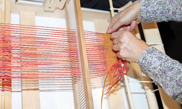 mani con telaio in legno per filatura tessuti e fili colorati
 - Foto, immagini