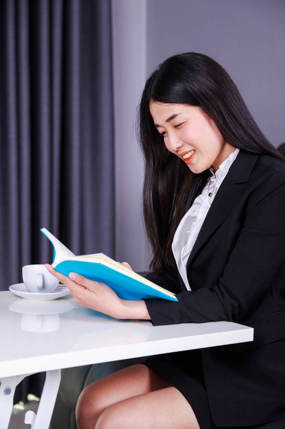 mulher de negócios sentado na mesa e lendo um livro
 - Foto, Imagem