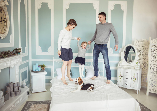 concept of family happiness: loving parents playing with baby daughter on bed in bedroom - Fotoğraf, Görsel
