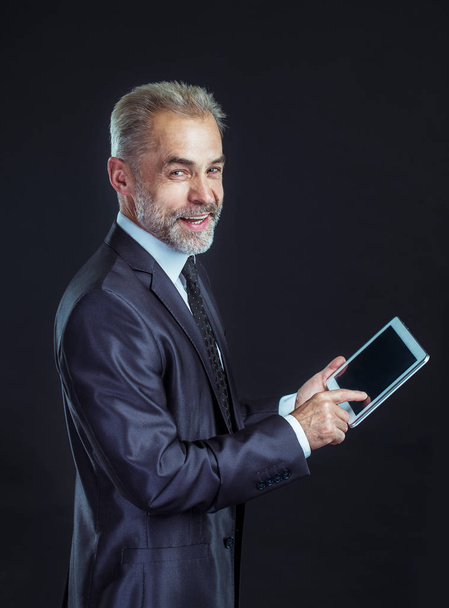 experienced businessman with digital tablet on black background. - Valokuva, kuva
