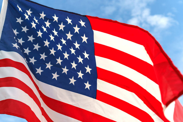 Κουνώντας το αστέρι και ρίγες αμερικανική σημαία στον γαλάζιο ουρανό - Φωτογραφία, εικόνα