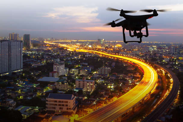 日没時に都市上空を飛行する無人機のシルエット - 写真・画像