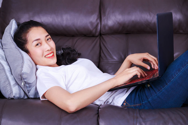 young woman using a laptop computer on sofa in living room at ho - Fotografie, Obrázek