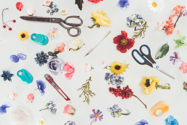 Draufsicht auf farbige Blumen mit Schere und Schreibwarenmesser isoliert auf weiß - Foto, Bild