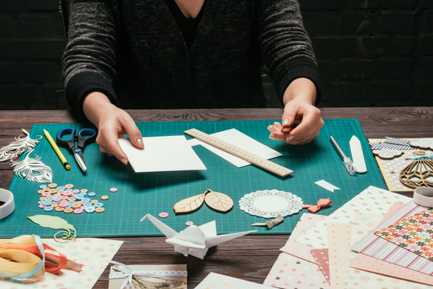 обрезанное изображение дизайнера, держащего лист бумаги для скрапбукинга открытки ручной работы
 - Фото, изображение