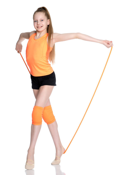 A girl gymnast performs exercises with a skipping rope. - 写真・画像