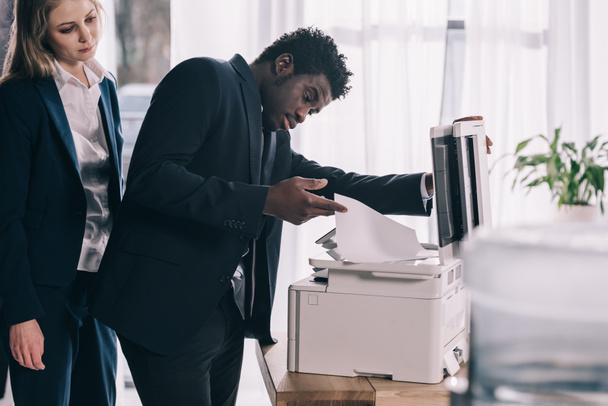 перевантажений афроамериканський менеджер, який використовує копіювальний апарат в офісі
 - Фото, зображення