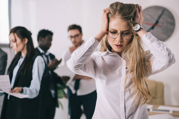 bewildered young businesswoman holding head in hands at office - Valokuva, kuva