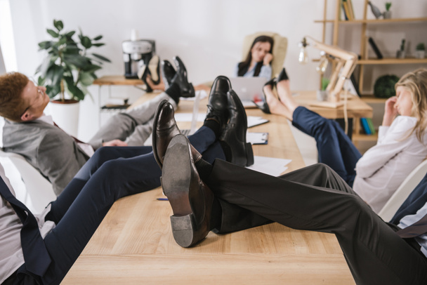 Бизнесмены сидят в конференц-зале с ногами на столе
 - Фото, изображение