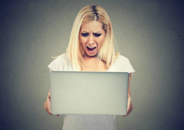 Shocked woman looking at laptop computer anxious with open mouth. - Foto, afbeelding