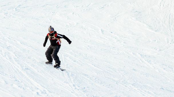 Young man rides snowboard on mountain slopes. - Fotó, kép