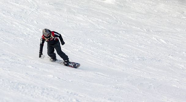 Young man rides snowboard and enjoying a winter day on mountain slopes. - Photo, image