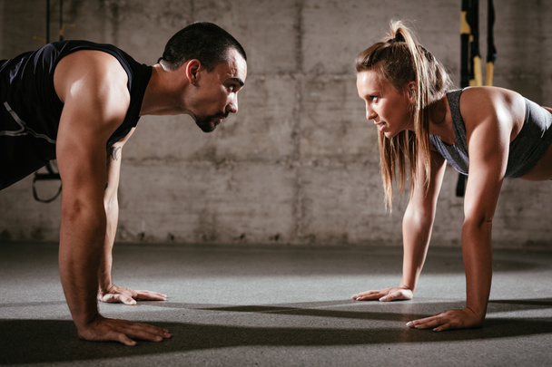 Young muscular couple doing push-up exercise at the cross fit workout. - Photo, Image