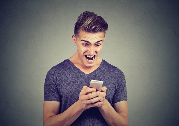Frustrated angry man reading a text message on smartphone screaming  - Foto, immagini