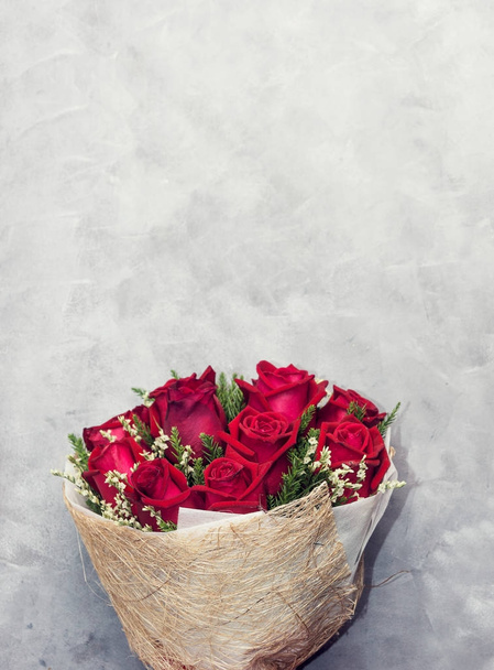Beautiful deep red rose bouquet on grey concrete background. Valentine's day, wedding decor concept. Text space - Фото, изображение