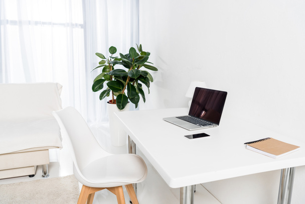laptop met leeg scherm, laptop, smartphone op tafel in het kantoor aan huis - Foto, afbeelding