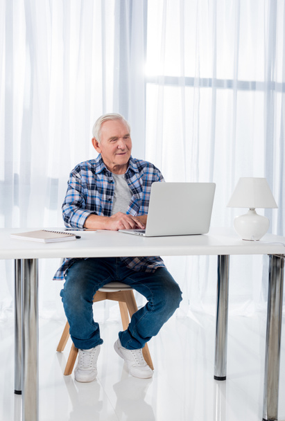 hombre mayor sentado en la mesa y el uso de la computadora portátil en casa
 - Foto, Imagen