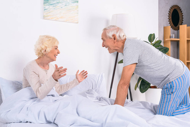 Seitenansicht der glücklichen älteren Frau und des Ehemannes, die zu Hause im Bett liegen - Foto, Bild