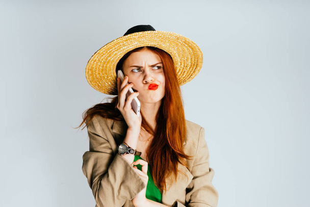 Young girl in a hat smiles worriedly talking on the phone - Photo, image