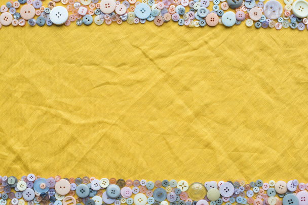 top view of colorful buttons frame on yellow cloth background with copy space - 写真・画像