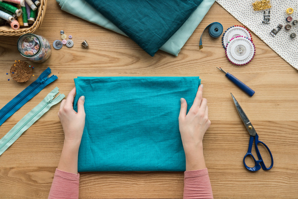 vista superior de las manos femeninas recortadas tela plegable en el lugar de trabajo costurera
 - Foto, Imagen