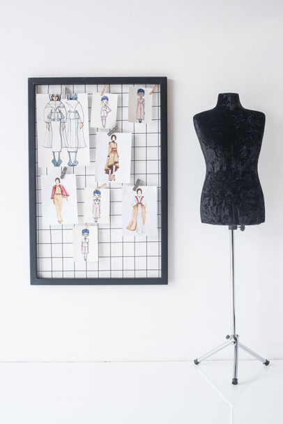 frame with fashion sketches hanged on white checkered background and black mannequin - Photo, Image