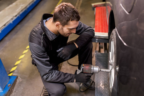 auto mechanic with screwdriver changing car tire - Фото, зображення