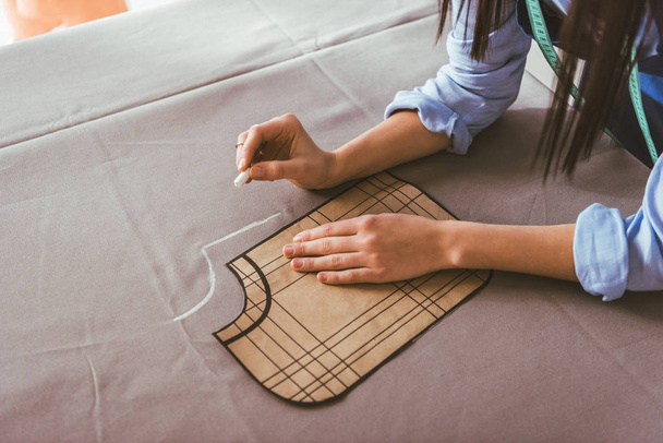 cropped image of seamstress making pattern with piece of chalk on fabric  - Photo, Image