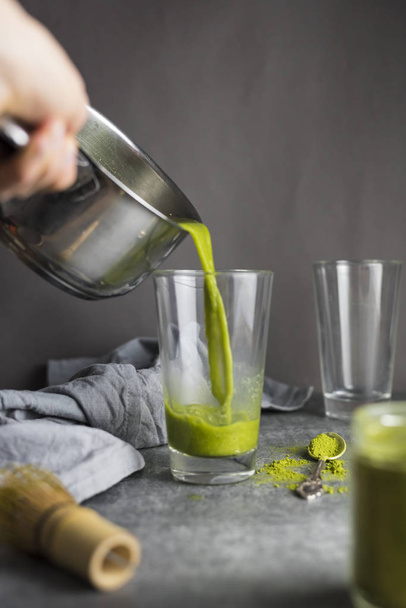 Женщина наливает зеленый чай маття в стакан
 - Фото, изображение