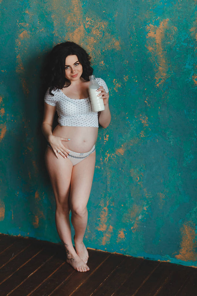Donna incinta con in mano una bottiglia di latte. Nutri il feto e il suo corpo per rimanere in salute e sempre
. - Foto, immagini