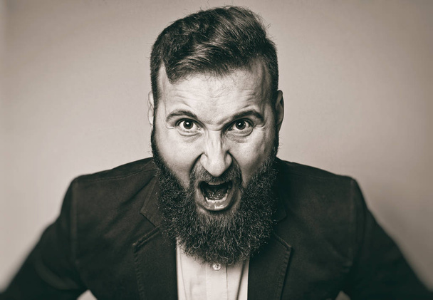 Понятие гнева. Бородатый мужчина в костюме кричит в состоянии гнева. Черно-белое изображение в винтажном стиле
.  - Фото, изображение