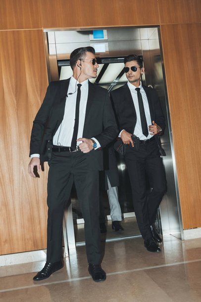 guardaespaldas revisando territorio al salir del ascensor con hombre de negocios
  - Foto, Imagen
